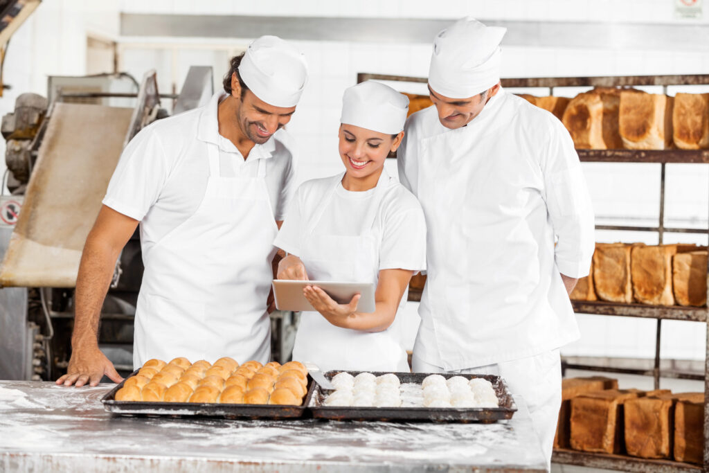 Drei Bäcker in der Backstube beim Benutzen der Bäckerei Software